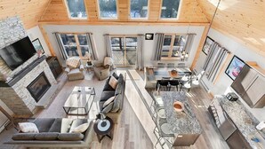 A spacious interior with a fireplace, seating area, kitchen, and large windows.
