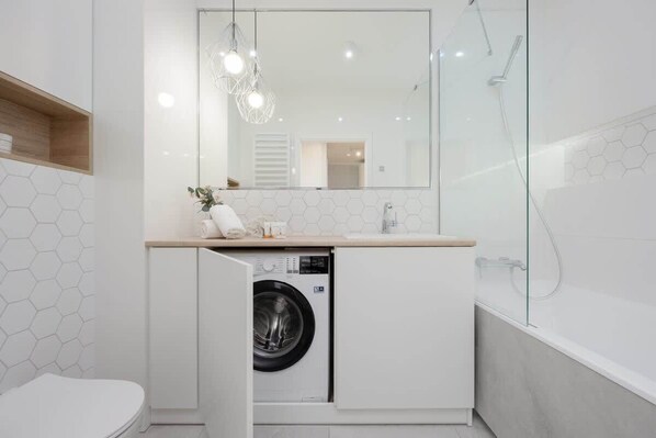 Bathroom with a bathtub with shower function, toilet, hair dryer and washing machine