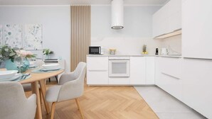 Een moderne keuken met witte kasten, een centraal eiland en een eethoek met een houten tafel en stoelen.