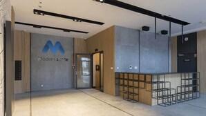 A modern interior with a reception desk, a glass door entrance, and a logo on the wall. - Charming Apartment with Balcony | Close to Chopin Airport (Warszawa)