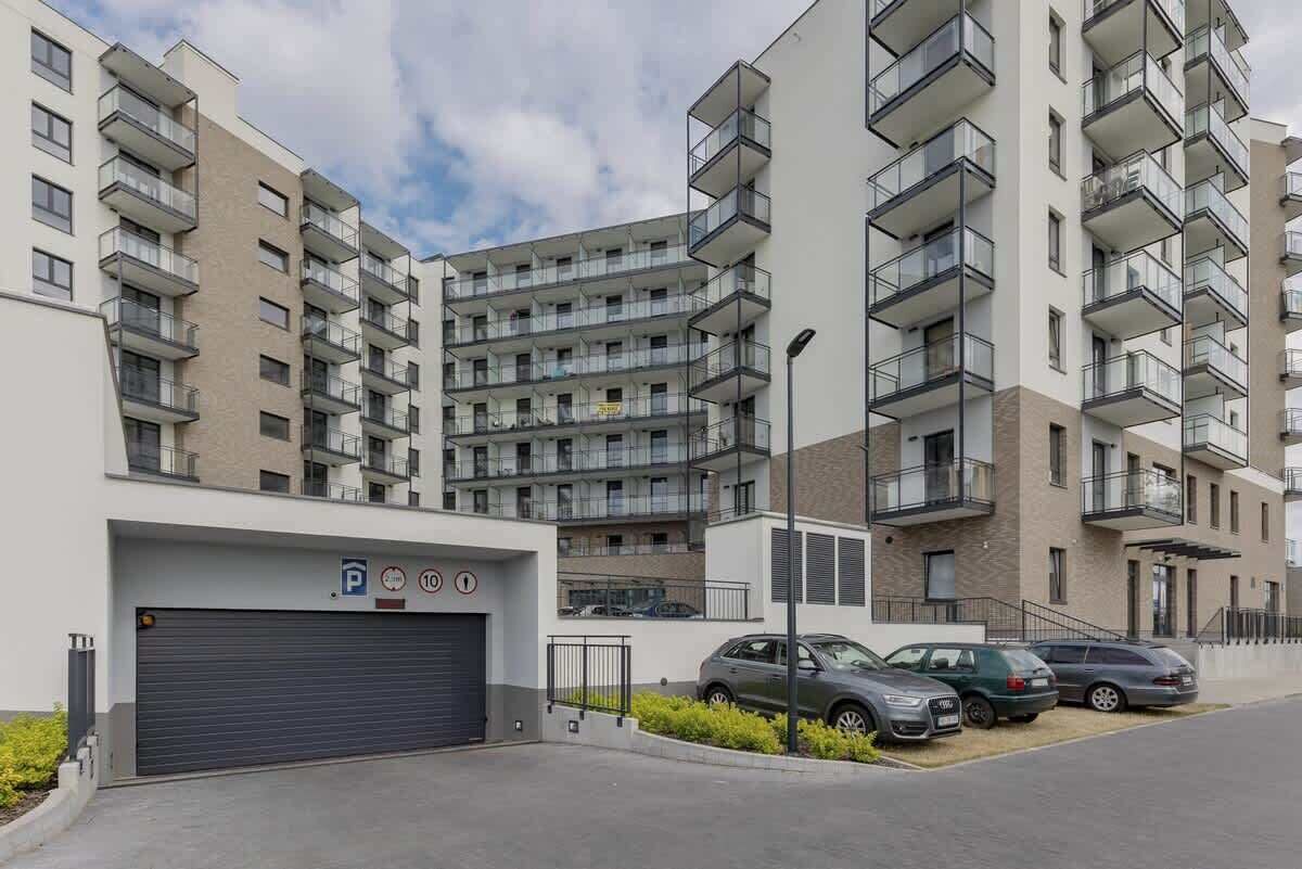 A multi-story residential building with balconies, a parking garage, and a clear sky.