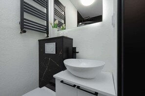 A modern bathroom with a white sink, black marble cabinet, and a mirror above the sink. - Stylish Studio in the center of Lodz | Smart TV | WiFi (Lódz)