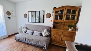 Un salon avec un canapé gris, un meuble en bois et un grand miroir accroché au mur.