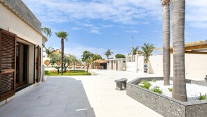 Un pati amb piscina, palmeres i zona de seients coberta.