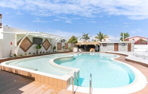 A swimming pool with a curved edge, surrounded by a wooden deck and a covered seating area. - Awesome home in Punta Milocca (Punta Milocca)