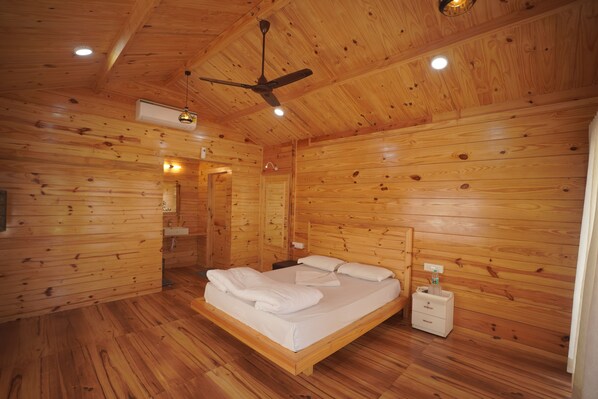 A wooden-paneled room with a bed, a ceiling fan, and a nightstand. - The Candlewood Resort (Murud)