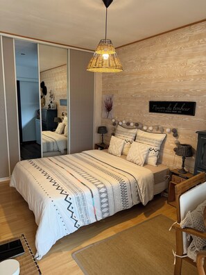 A bedroom with a bed, bedside tables, a hanging light fixture, a mirror, and a wall-mounted sign. - A natural, cozy oasis just 25 minutes from Bordeaux. (LA LANDE DE FRONSAC)