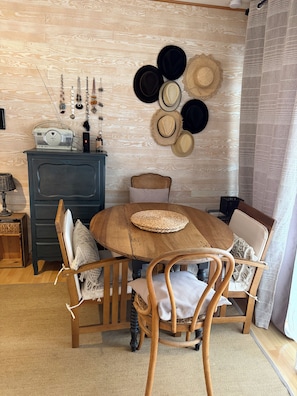 A wooden dining table with a woven placemat, surrounded by wooden chairs with cushions.