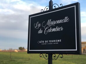 Un letrero de 'La Maisonette du Colombier' que describe el lugar como sitio turístico, destacando comodidades, tranquilidad y naturaleza.