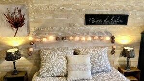 A bedroom with a wooden headboard, decorative lights, patterned bedding, and two bedside lamps.