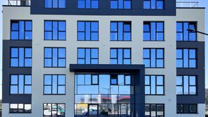 A modern multi-story building with large windows and a central entrance. - LikeDaheim Apartments (Rosbach vor der Hoehe)