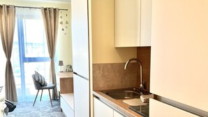 A modern kitchen with a sink, cabinets, and a chair in the background. - LikeDaheim Apartments (Rosbach vor der Hoehe)