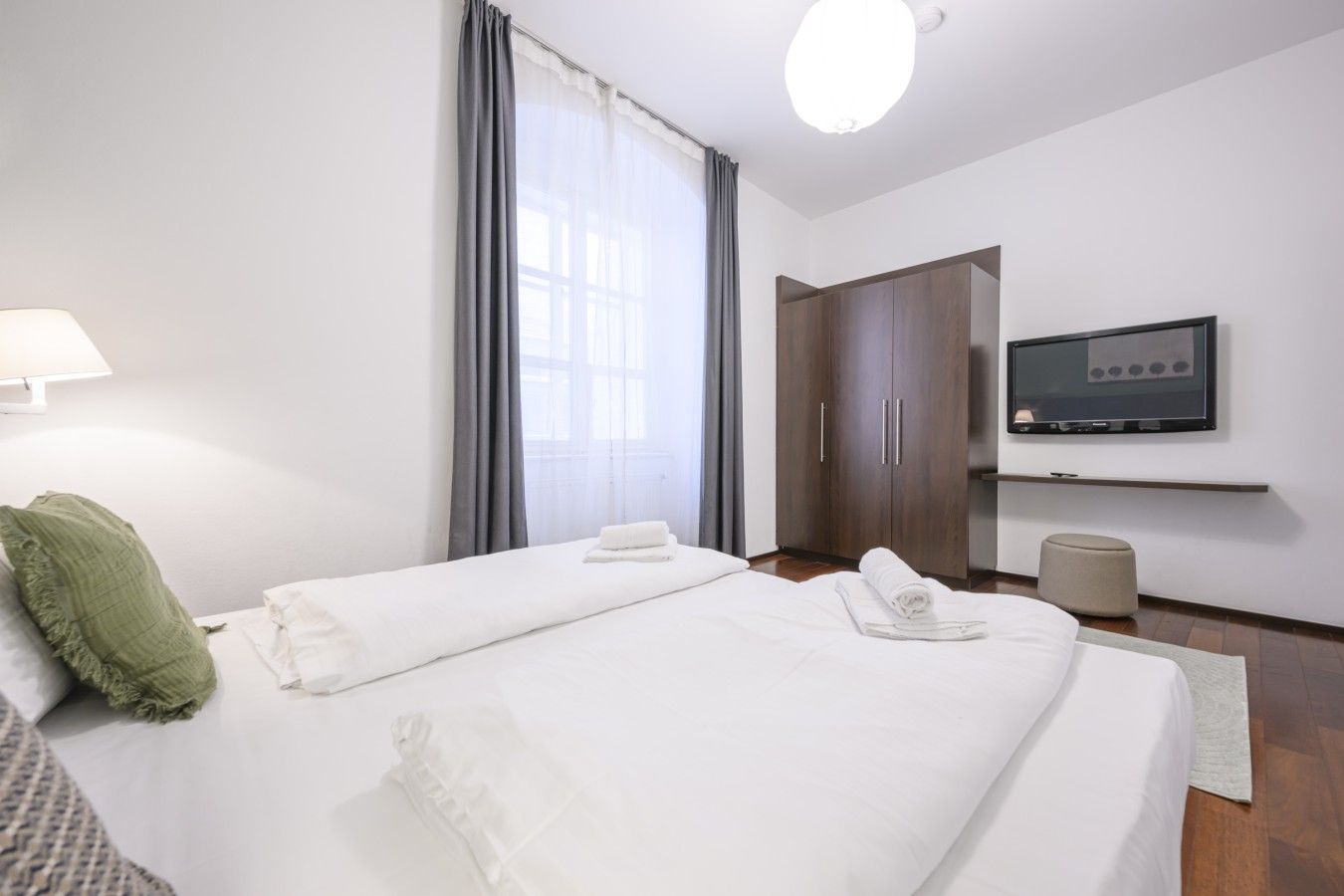 Ein Hotelzimmer mit zwei Betten, einem Fernseher, einem Kleiderschrank und einem Fenster mit Vorhängen.