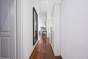 A hallway with a wooden floor, white walls, and a framed picture on the left. - Premium Business Apartment (Vienna)