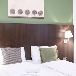 A hotel room with a wooden headboard, a wall-mounted lamp, and a painting of trees. - Premium Business Apartment (Vienna)
