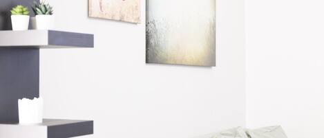 A modern living room with a grey sofa, a black shelving unit, and two abstract paintings.