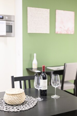 Uma mesa com uma garrafa de vinho, duas taças e uma cesta de palha sobre um jogo americano.