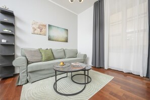 A modern living room with a grey sofa, a coffee table, and a bookshelf.