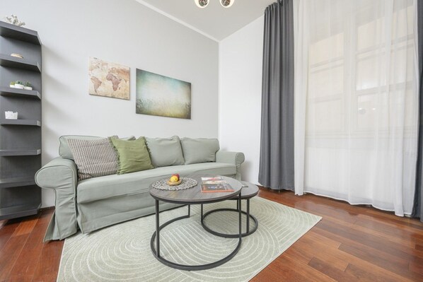 A modern living room with a grey sofa, a coffee table, and a bookshelf.