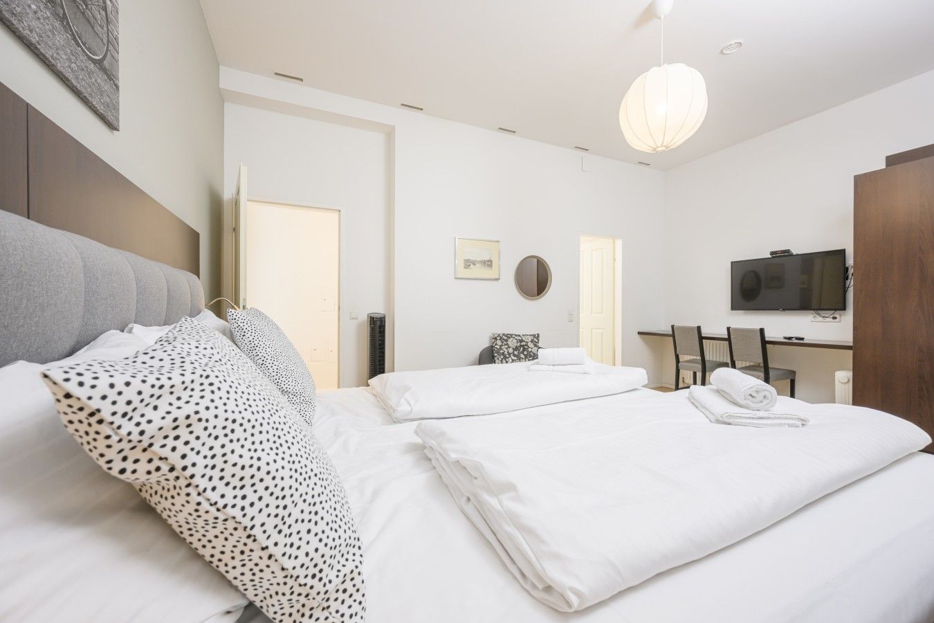 Une chambre d’hôtel avec un lit, un bureau, une télévision et un miroir.
