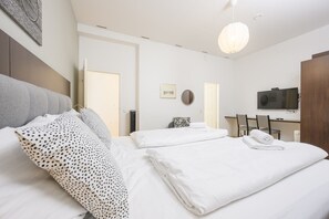 Habitación de hotel con cama, escritorio, televisor y espejo.