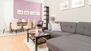 Ein modernes Wohnzimmer mit grauem Sofa, einem Couchtisch und einem Essbereich mit Stühlen und Tisch.