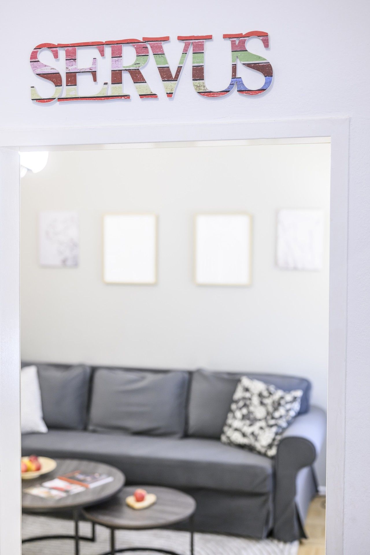 Un salon avec un canapé gris, une table basse et deux tableaux encadrés accrochés au mur.
