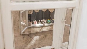 Ein Fenster mit Blick auf einen Balkonbereich, inklusive eines fensters mit Vorhängen und einem Regal mit verschiedenen Gegenständen.