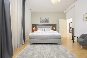 A modern bedroom with a bed, bedside lamps, a headboard, a rug, and a chair.