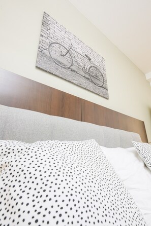 Una cama con un cojín de lunares y una obra de arte en la pared con un dibujo de una bicicleta.