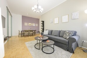 A modern living room with a grey sofa, two round coffee tables, and a chandelier.