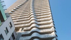 Un edificio moderno de gran altura con una fachada ondulada distintiva y balcones.