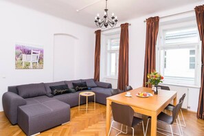 Un salon moderne avec un canapé, une table à manger et un lustre.