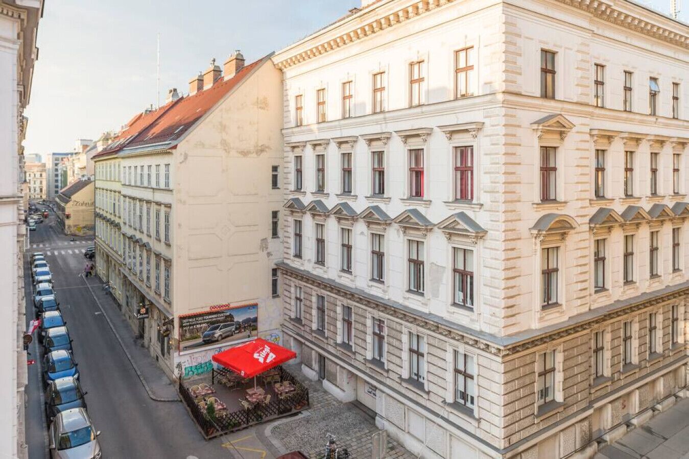 A historic building with a row of windows, a red awning, and a street view.