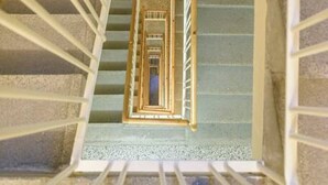 A staircase with a wooden handrail and white balusters, leading to a landing with a view of the interior. - Kriehubergasse / Margaretengürtel (Vienna)