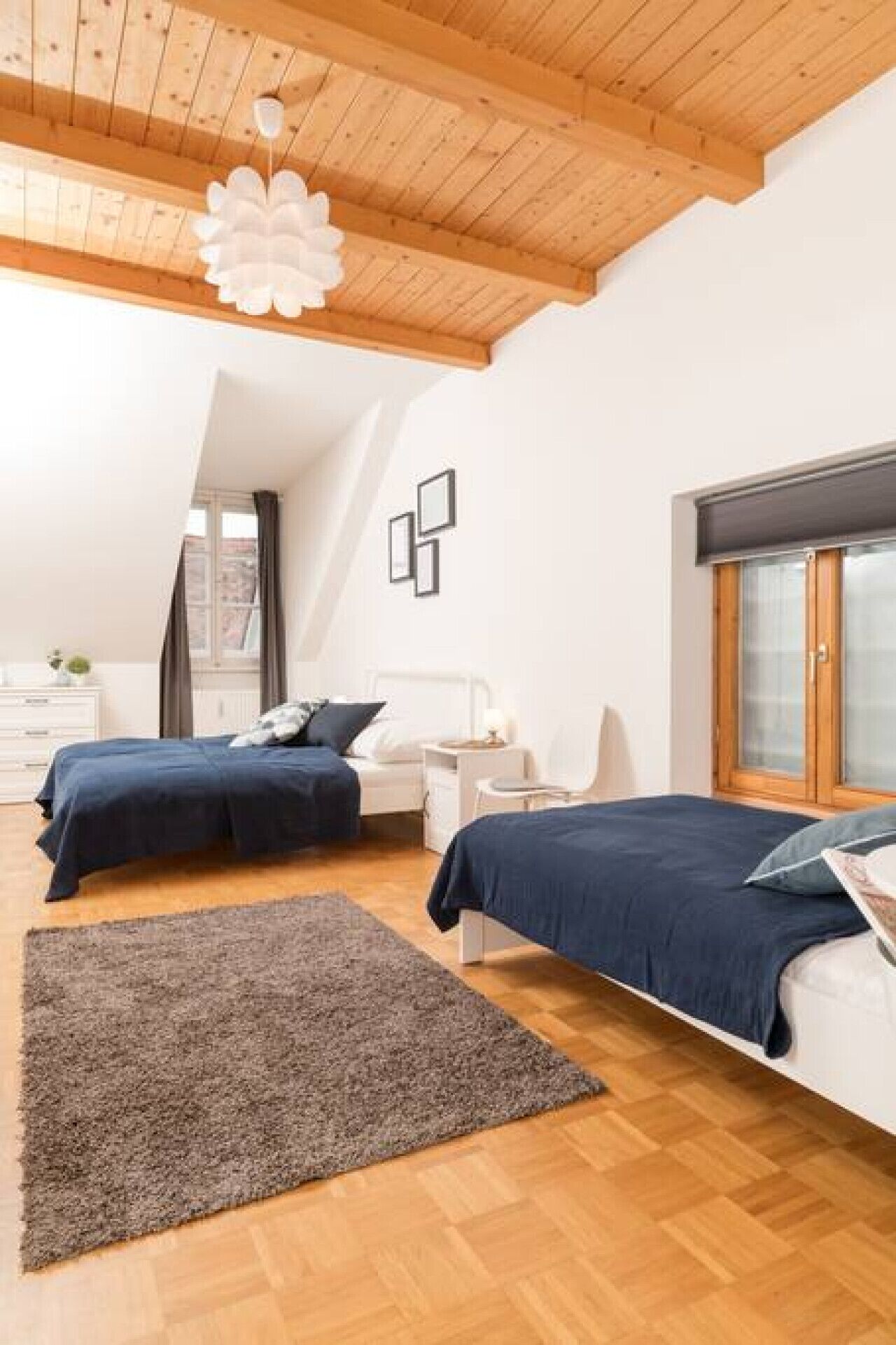 Une chambre avec deux lits, un plafond en bois et une grande fenêtre.