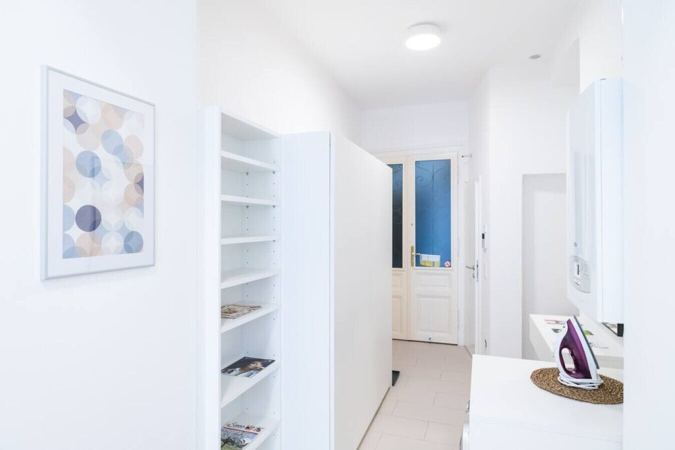 Un couloir aux murs blancs, avec une bibliothèque et une porte donnant sur une salle de bain.
