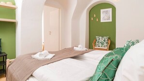 A hotel room with a bed, a chair, and a green wall.