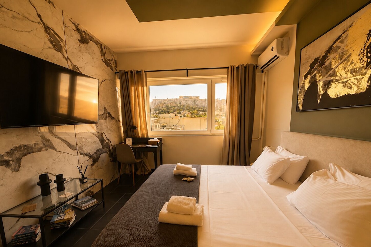 Quarto de hotel com cama, escrivaninha, cadeira, televisão, janela com vista para a cidade e estante de livros.