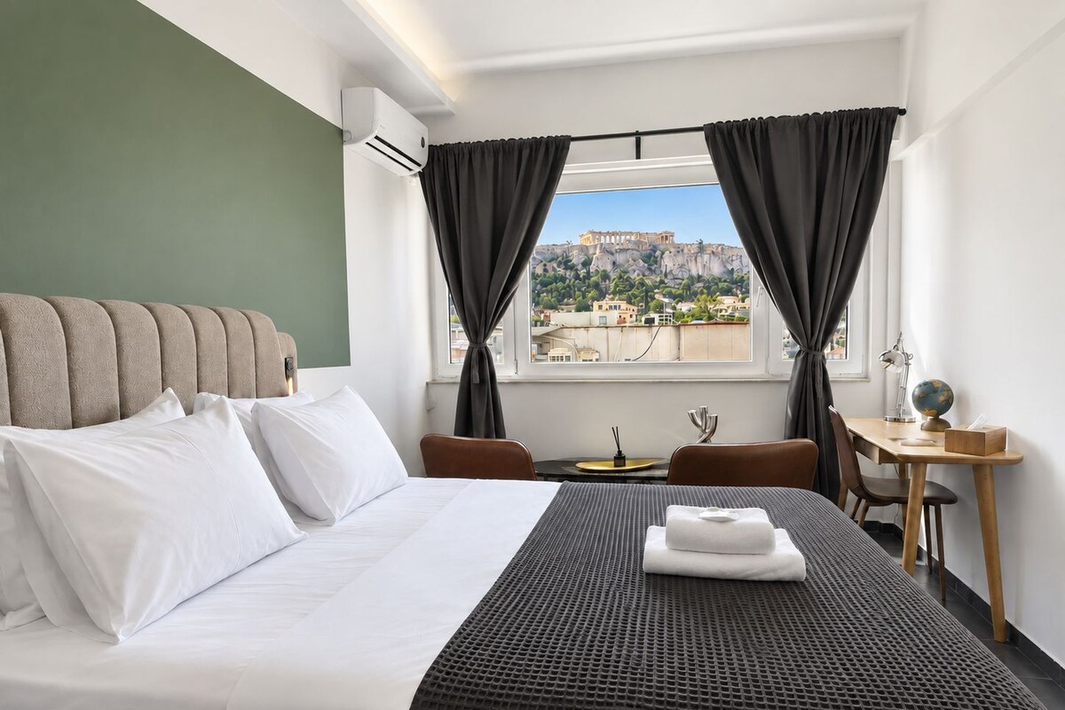 A hotel room with a bed, a desk, and a view of a historical building.