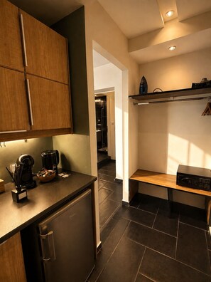 A modern kitchen with dark cabinetry, a built-in refrigerator, and a coffee station. - Elite Ermou Suites (Athens)