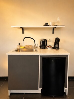 A compact kitchen with a sink, a coffee maker, and a dishwasher. - Elite Ermou Suites (Athens)