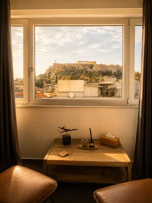 A room with a view of a historic building, a small table with a plant, a cup, and a tissue box. - Elite Ermou Suites (Athens)