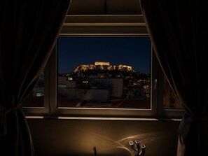A view of a historic building illuminated at night, seen through a window with curtains. - Elite Ermou Suites (Athens)