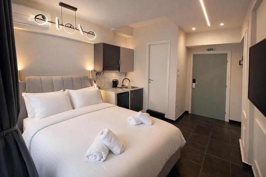 A hotel room with a bed, a desk, a sink, and a television.