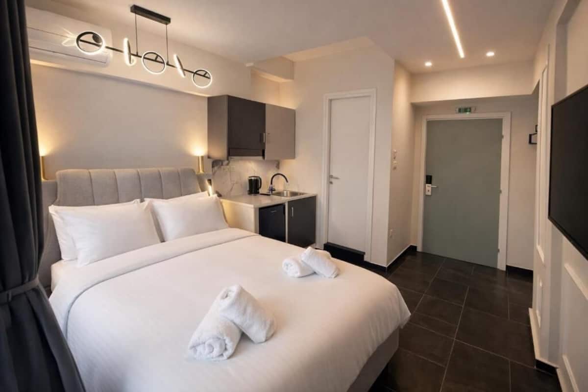 A hotel room with a bed, a desk, a sink, and a television.