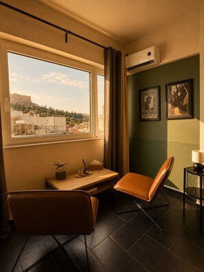 A room with a desk, two chairs, a lamp, and a view of a cityscape. - Elite Ermou Suites (Athens)