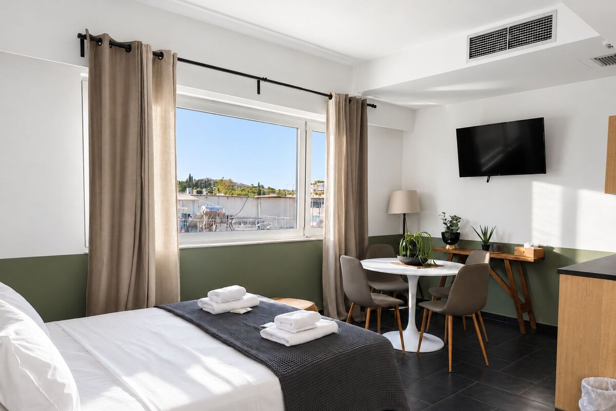 A hotel room with a bed, a desk, a chair, a TV, and a window with curtains.