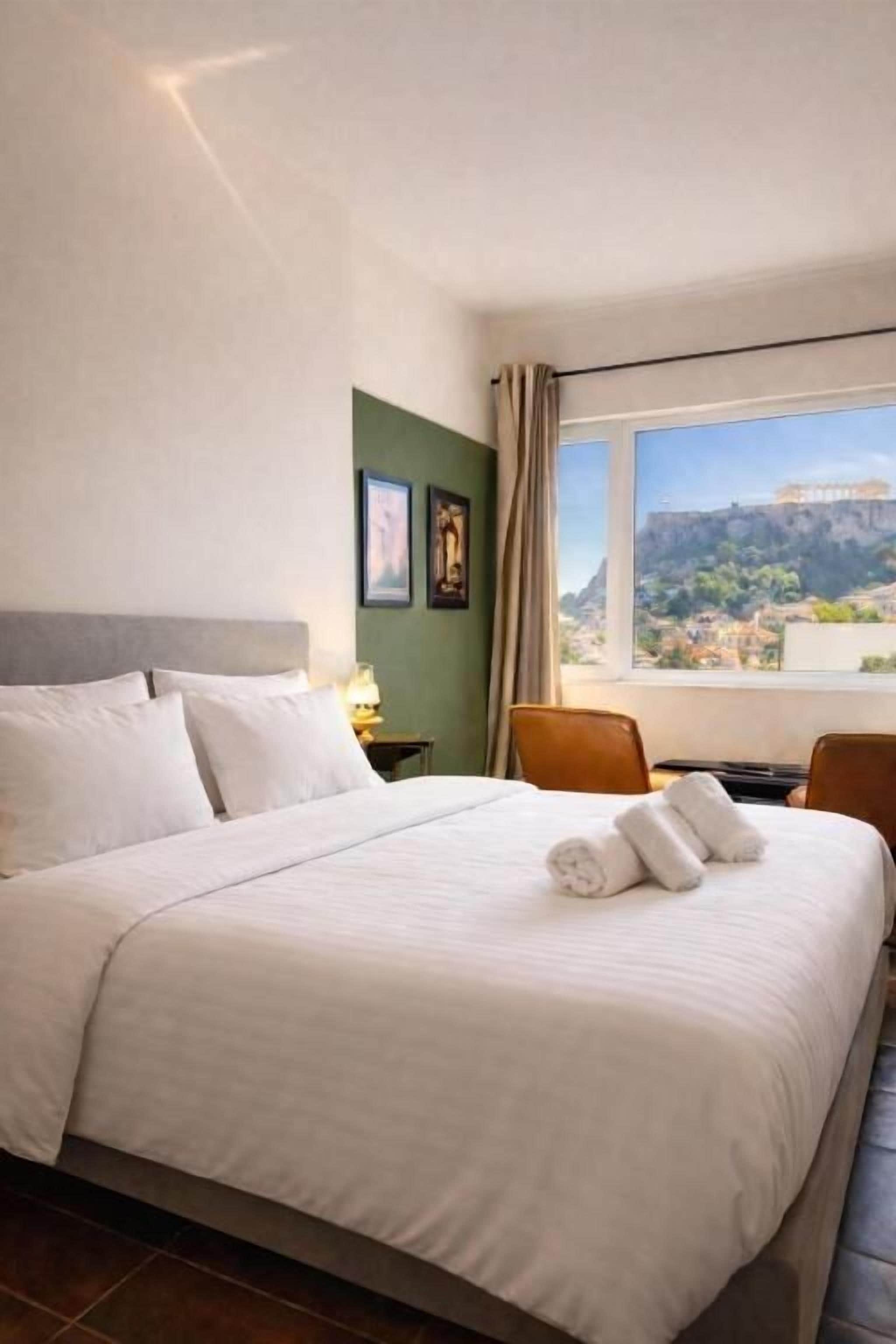 A hotel room with a large bed, a view of a cityscape, and a green wall.