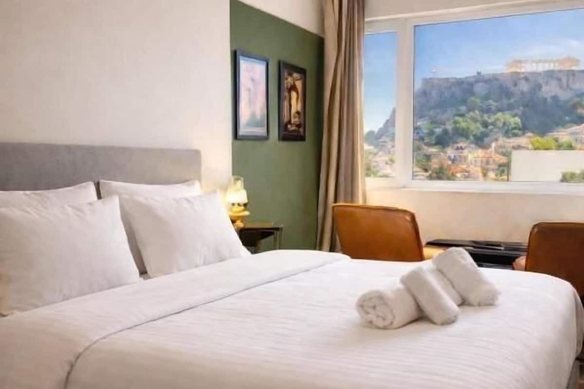 A hotel room with a large bed, a view of a cityscape, and a green wall.